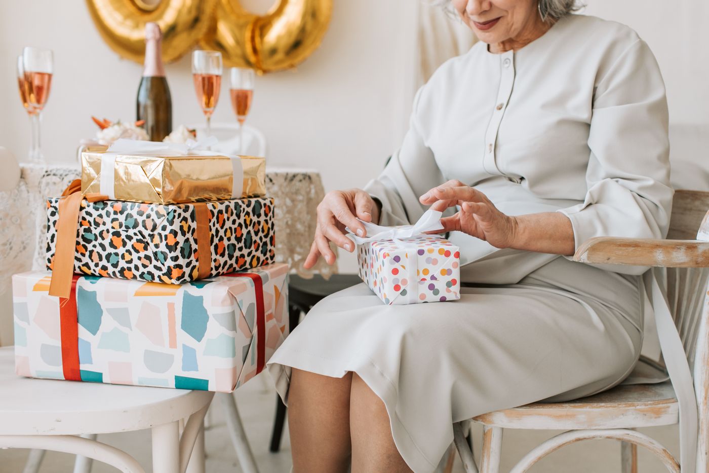 A woman opening a carefully wrapped birthday gift